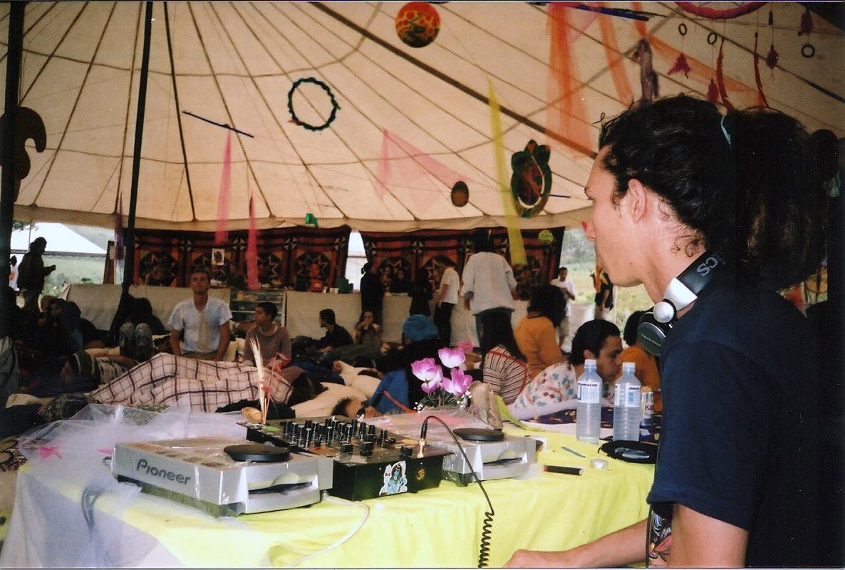 a DJ behind CD decks inside a tent