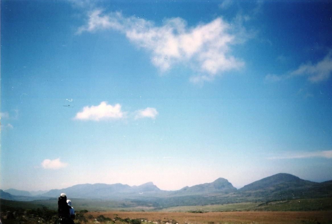a tiny figure with a backpack under a huge sky
