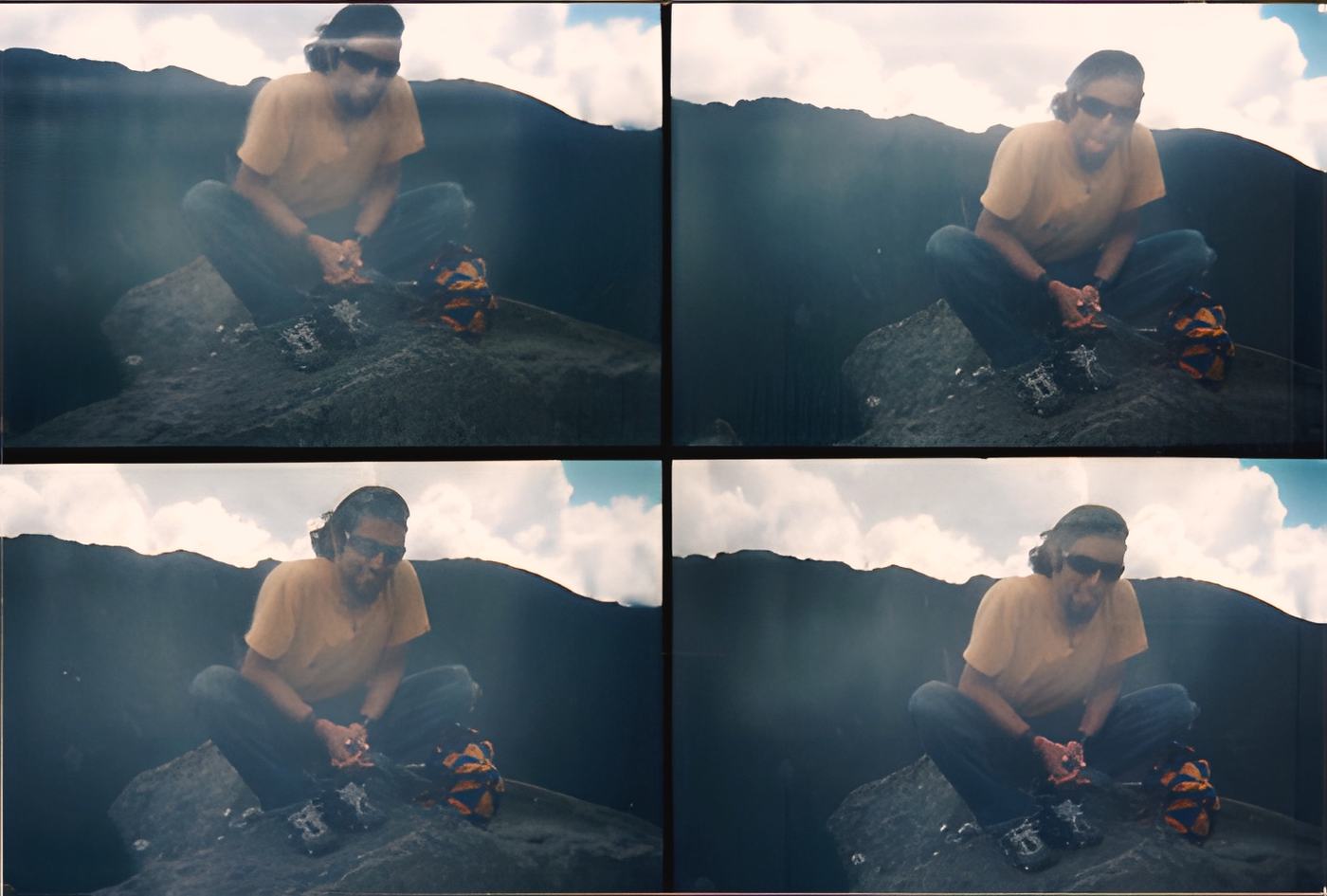 a man on a rock, a dark ridge and clouds behind