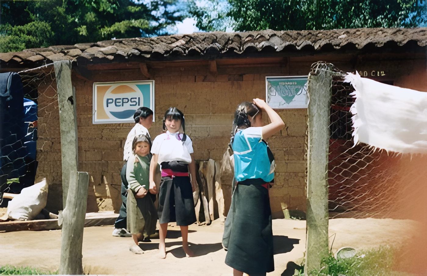 women and a child in dark skirts by an adobe house