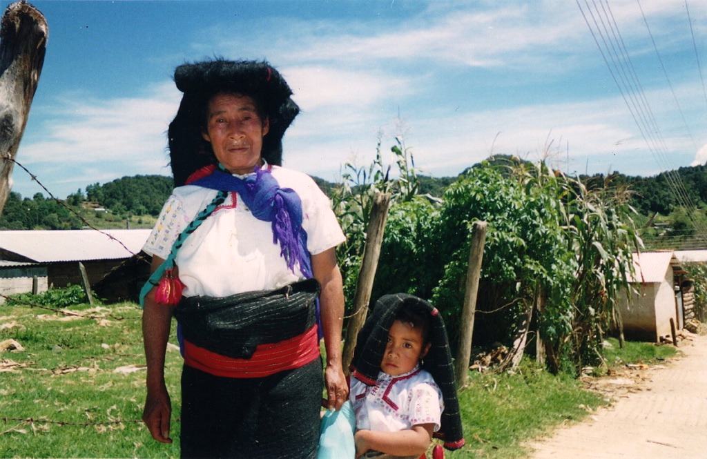 a woman and child in traditional dress by a cornfield
