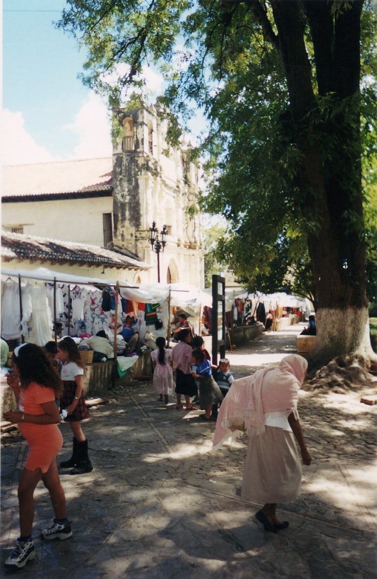 market stalls by a baroque church, a woman in pink