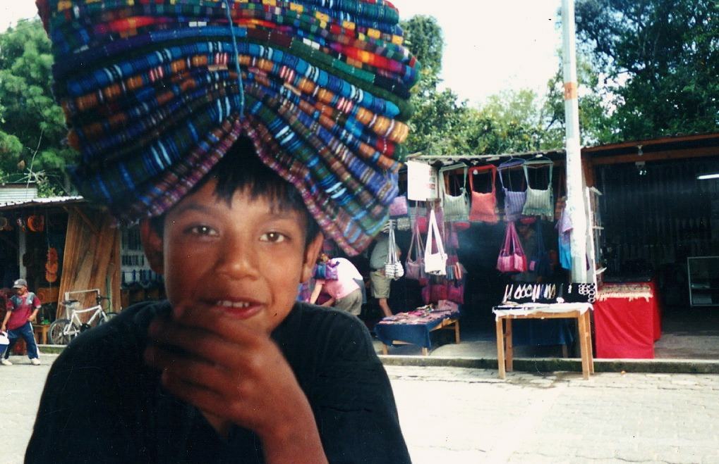 a boy carries woven textiles on his head