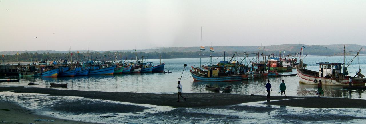 painted fishing boats moored in a calm bay, men walking along a sandbar in front, a wide view in several frames