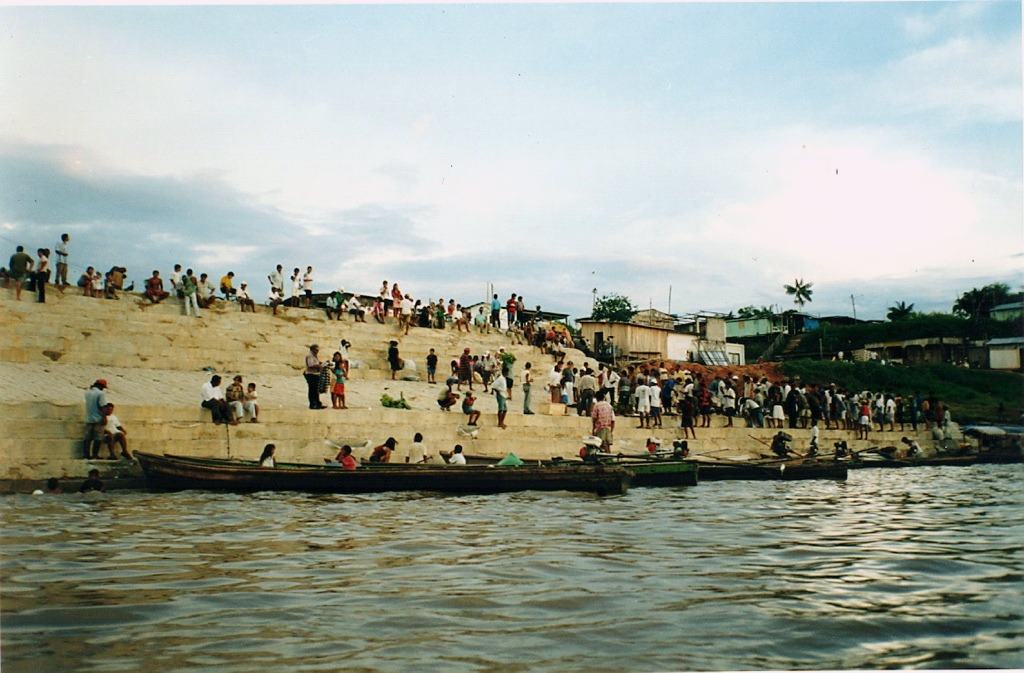 a crowd on river steps, boats moored below