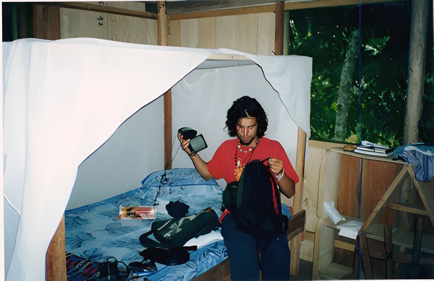 sitting on a bed under a mosquito net, camera in hand