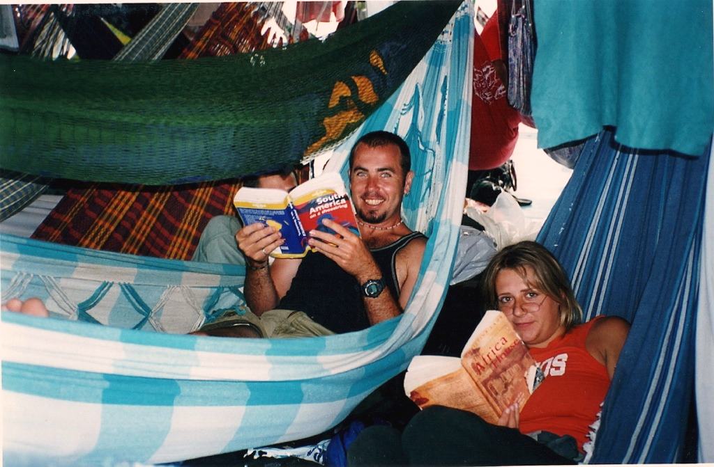 a man and woman in hammocks, holding up guidebooks