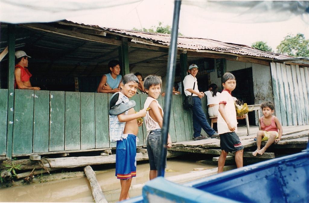 boys stand on a plank at a riverside building