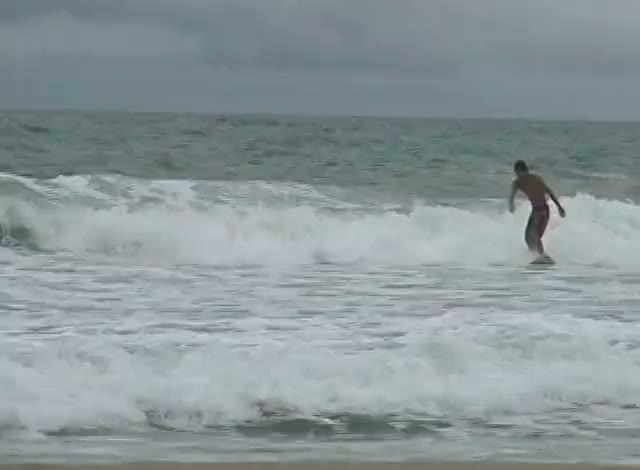 A surfer riding a breaking wave, white water and grey sea.
